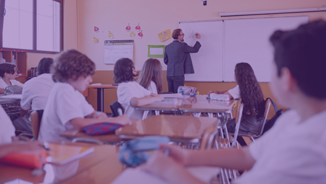 Skolotājs raksta uz tāfeles, skolēni klausās