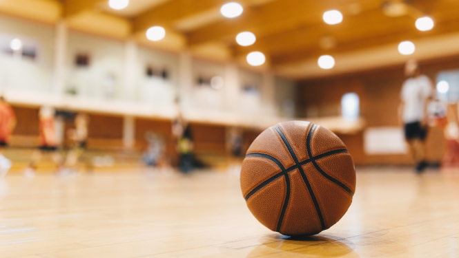 Sporta zāle, uz grīdas stāv basketbola bumba