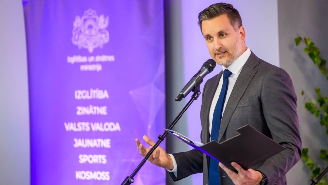 Izglītības un zinātnes ministrijas valsts sekretāra vietnieks sporta un jaunatnes jautājumos Edgars Pukinsks. Vīrietis pie mikrofona veic uzrunu.