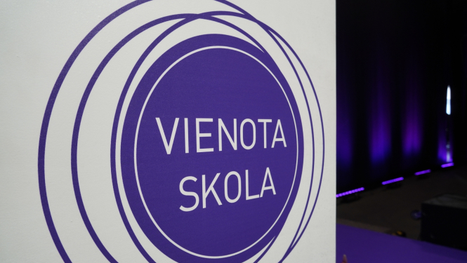 Attēlā redzams violets aplis ar violetām līnijām ap šo apli uz balta fona un uzraksts apļa vidū "Vienota skola"