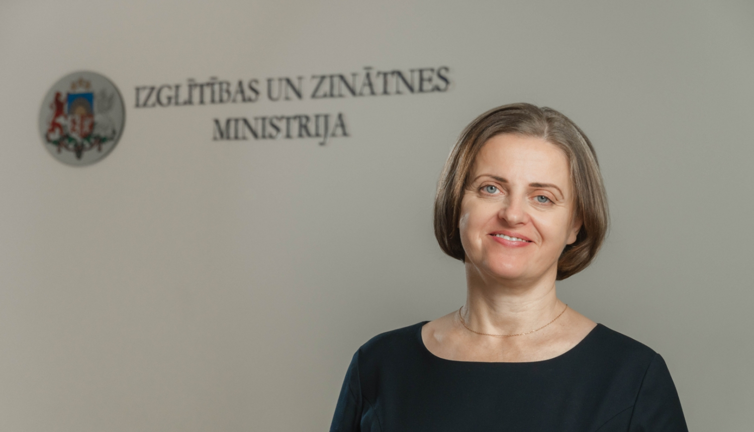 Edīte Kanaviņa, fonā Izglītības un zinātnes ministrijas logo