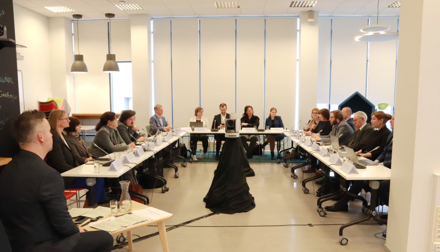 Akadēmiskās ētikas diskusijas dalībnieki sēž pie galdiem