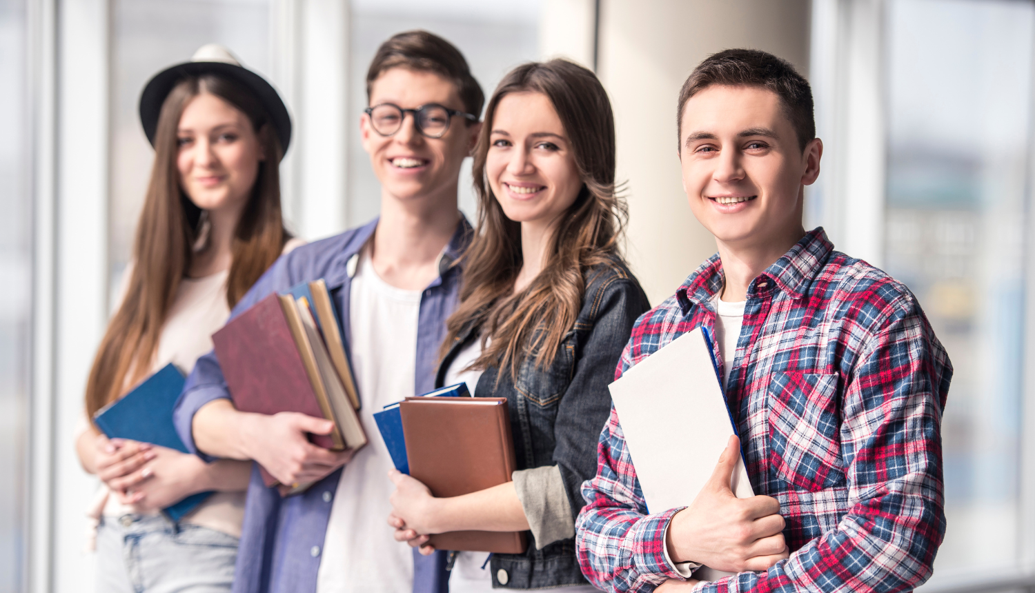 Divi studenti un divas studentes  ar grāmatām rokās