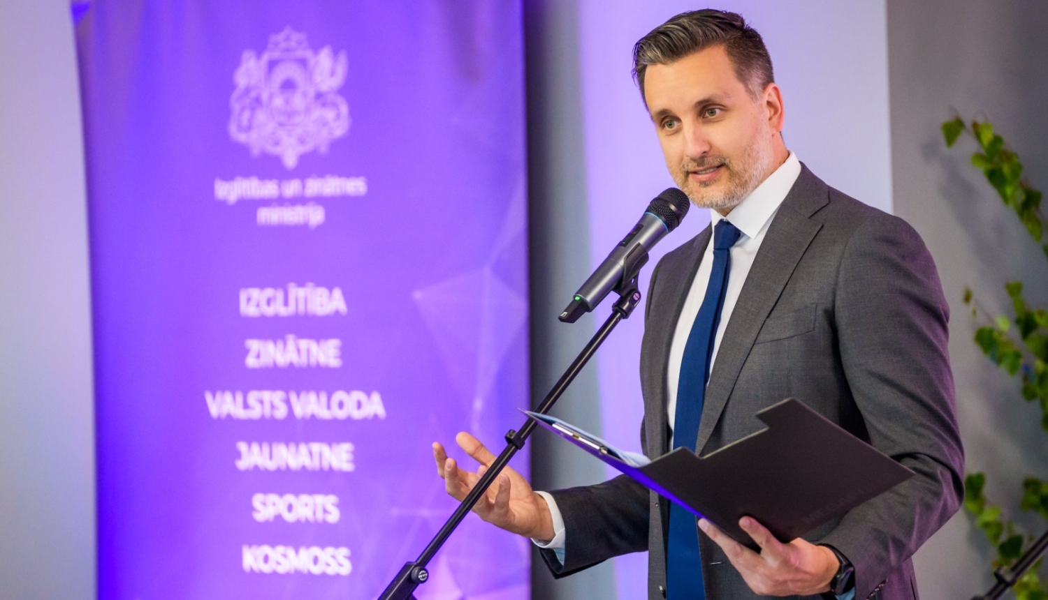 Izglītības un zinātnes ministrijas valsts sekretāra vietnieks sporta un jaunatnes jautājumos Edgars Pukinsks. Vīrietis pie mikrofona veic uzrunu.