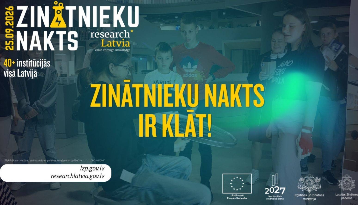 Cilvēki pēta kā zinātniece atrāda eksperimentu. Tekstā "25.09.2026. - Zinātnieku nakts ir klāt!"
