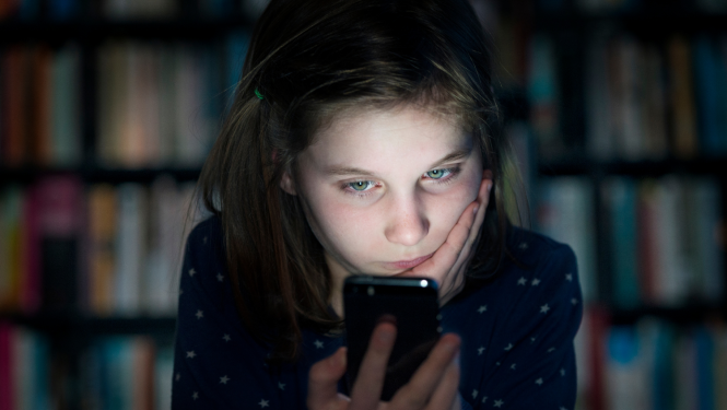 Tumsā meitene skatās telefona ekrānā