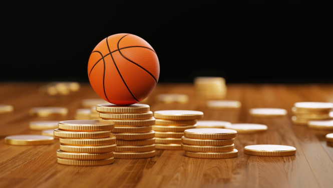 Izkaisītas naudas monētas uz galda, uz vienas no kollonām – basketbola bumba.