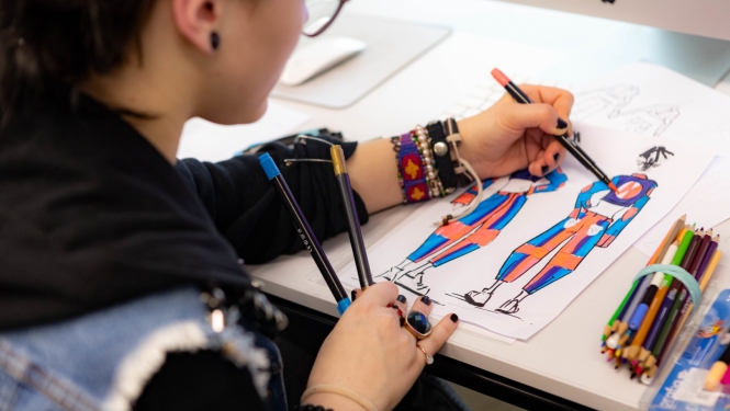 SkillsLatvia konkursa pusfinālā meitene zīmē tērpu skices