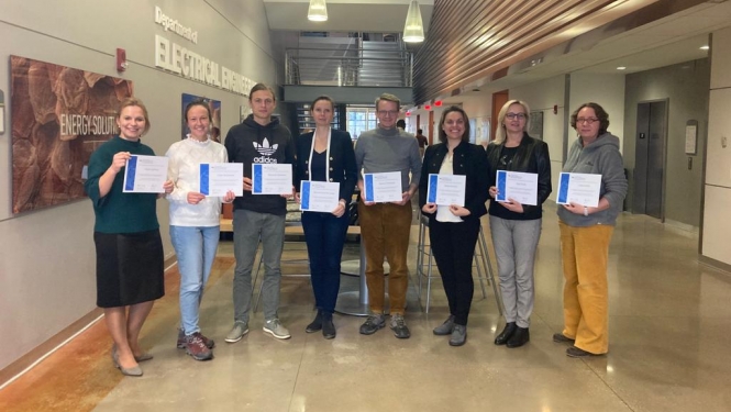 cilvēki gaitenī ar diplomiem
