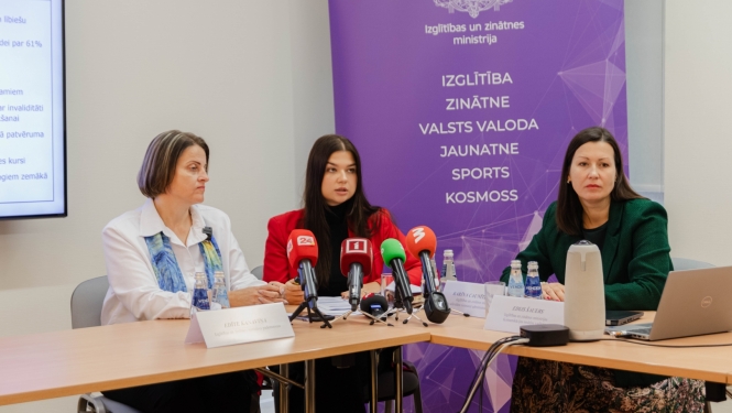 Pie galda sēž Edīte Kanaviņa, Silvija Amatniece un Karīna Caunīte-Orupe. Uz galda mediju mikrofoni, fonā uz violeta fona IZM logo un uzskaitītas zinātņu nozares: izglītība, zinātne, valsts valoda, jaunatne, sports, kosmoss