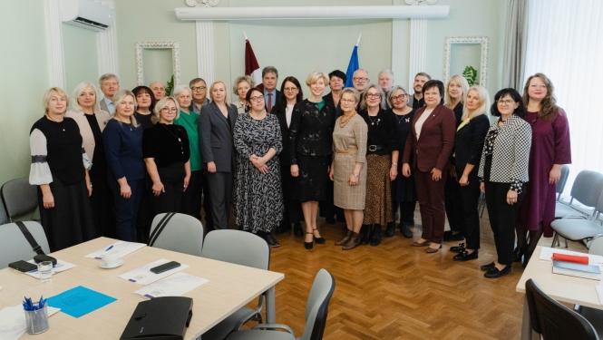Ministres un skolu direktoru kopbilde pie Latvijas un ES karogiem.