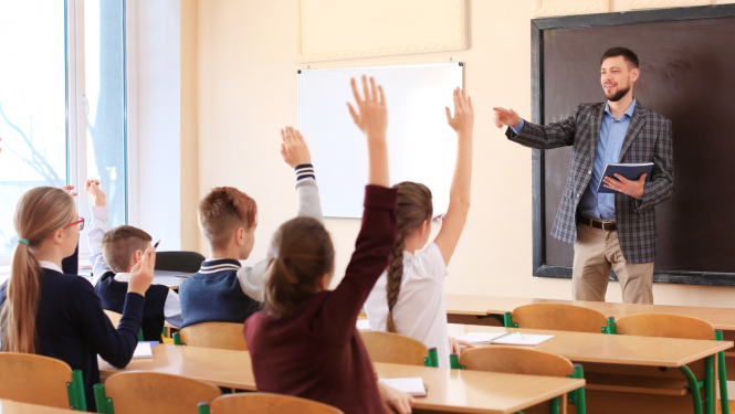 Klasē skolotājs jautā skolēniem un skolēni ceļ rokas