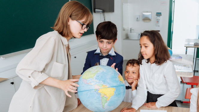 Skolotāja kopā ar bērniem pie globusa