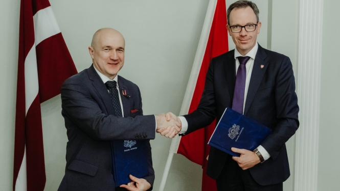 Uz Latvijas un Šveices karoga fona Šveices Konfederācijas vēstnieks Martēns Mišlē un Finanšu ministrijas valsts sekretāres vietnieks ES fondu jautājumos Armands Eberhards spiež viens otram roku