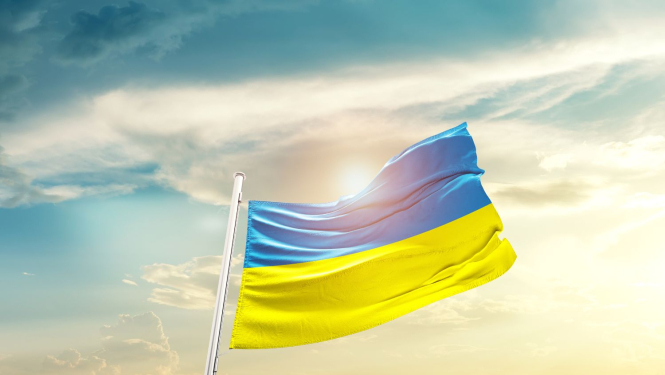 Ukrainas karogs plīvo vējā uz saulrieta fona