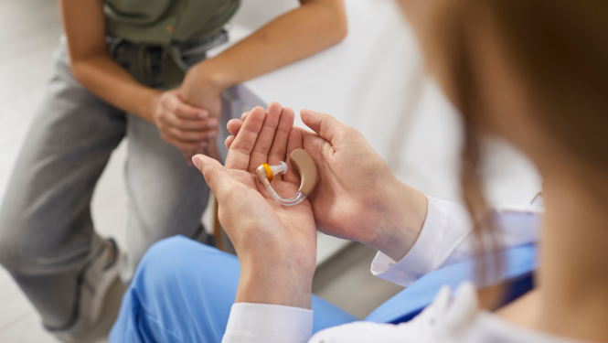 Sieviete rokās tur dzirdes aparātu