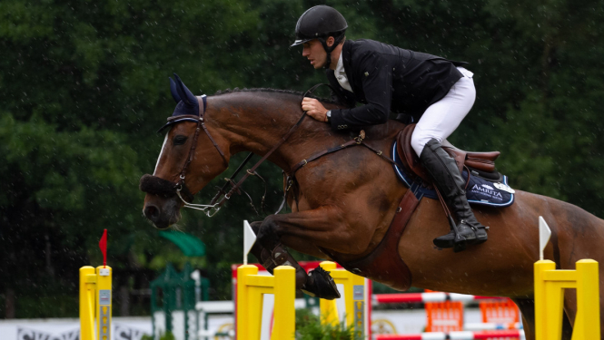 Jātnieks uz zirga lec pāri barjerai