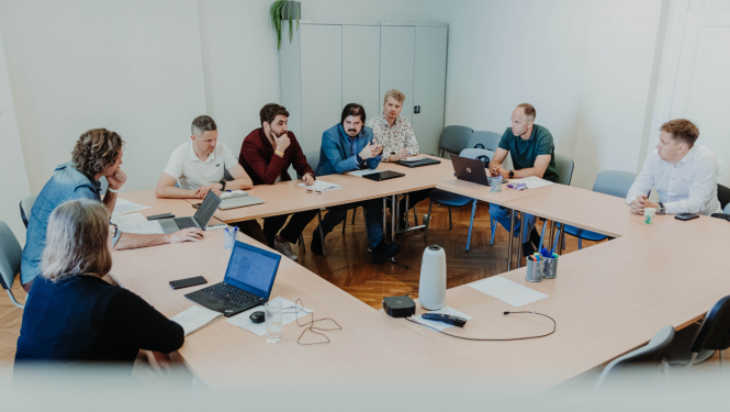 IZM uzsāk darbu pie jaunā sporta finansēšanas modeļa, cilvēki tikšanās sēdē sasēdušies ap galdu. 