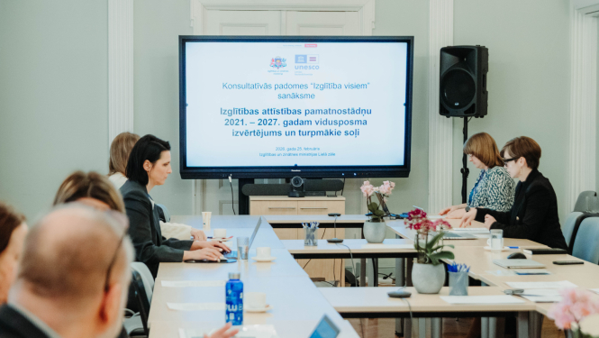 Sanāksmes dalībnieki, fonā redzams prezentācijas titulbilde