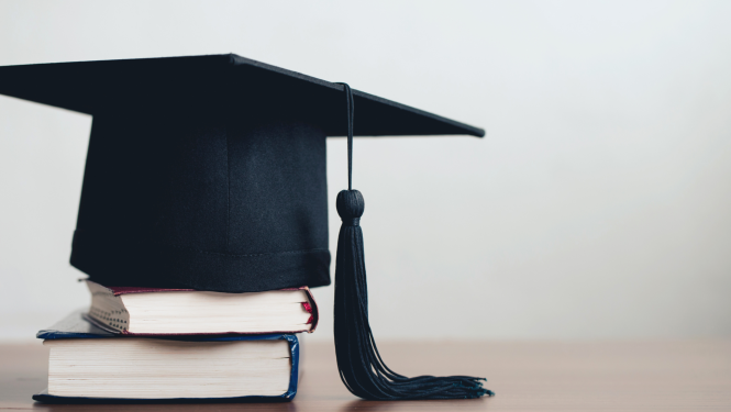 Absolventa cepure, kas novietota uz divām grāmatām.