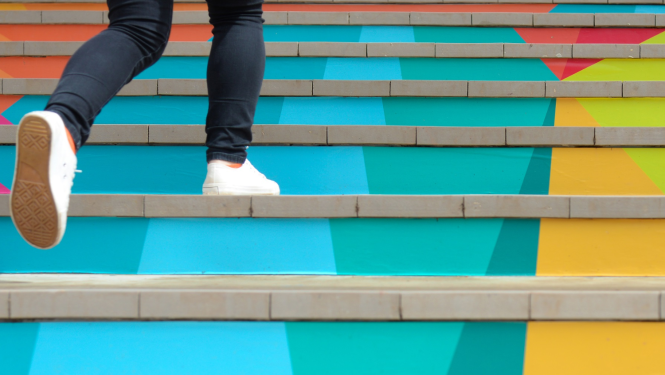 Cilvēks skrien augšā pa kāpnēm, kāpnes nokrāsotas dažādās krāsās. 