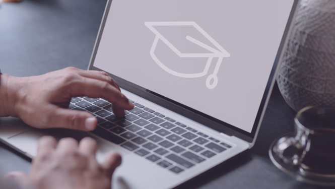 Cilvēks stradā pie datora, datorā redzams absolventu cepure