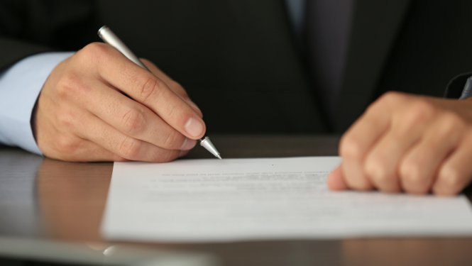 cilvēks paraksta dokumentu