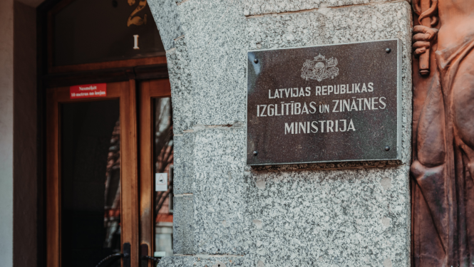 Izglītības un zinātnes ministrijas ieejas durvis, pie sienas plāksne ar IZM logo un uzrakstu