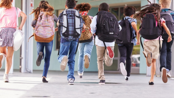 Skolēni ar mugursomām skrien uz skolu