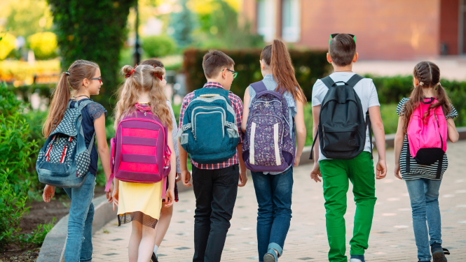 Skolēni ar mugursomām iet uz skolu.