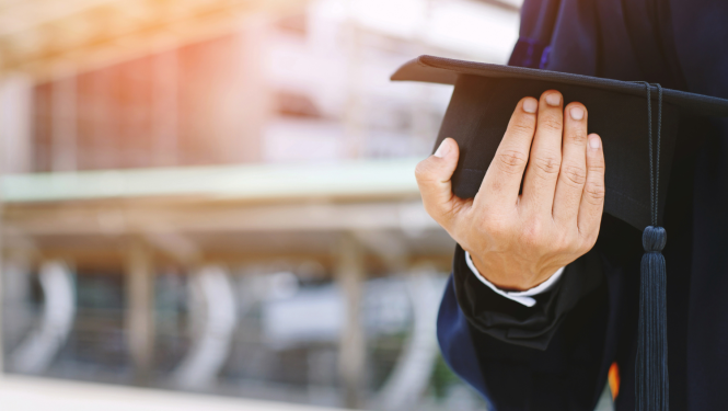 Students rokās tur absolventu cepurīti