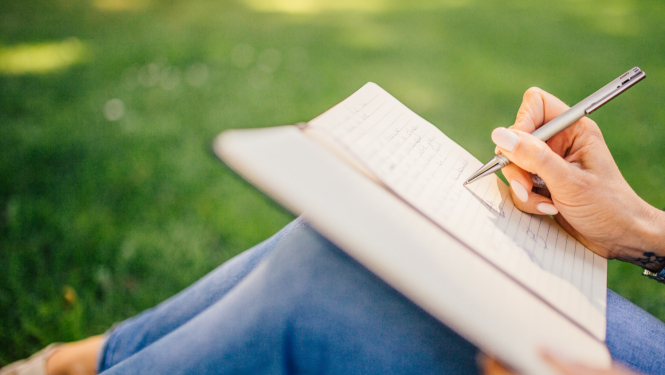 Cilvēks pieraksta piezīmes pierakstos ar pildspalvu