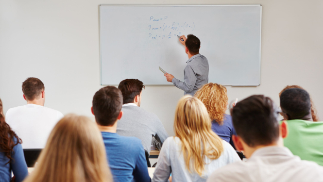 Pedagogs raksta uz tāfeles, skolēni skatās