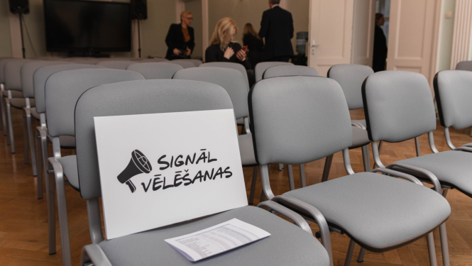 IZM lielajā zālē novietoti krēsli, uz krēsla stāv zīme ar uzrakstu "Signālvēlēšanas"