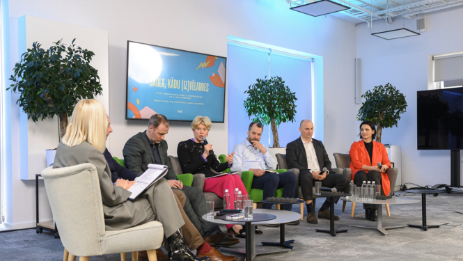 Izglītības un zinātnes ministre Anda Čakša piedalās diskusijā; septiņi cilvēki sēž pusaplī, ministre runā mikrofonā