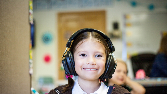 meitene skolas solā ar audio austiņām 