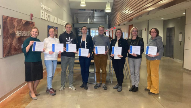 cilvēki gaitenī ar diplomiem