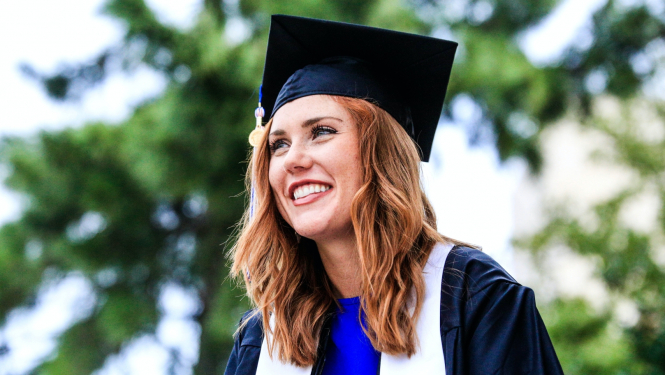 meitene absolventu kostīmā smaida