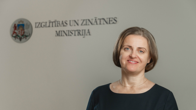 Edīte Kanaviņa, fonā Izglītības un zinātnes ministrijas logo