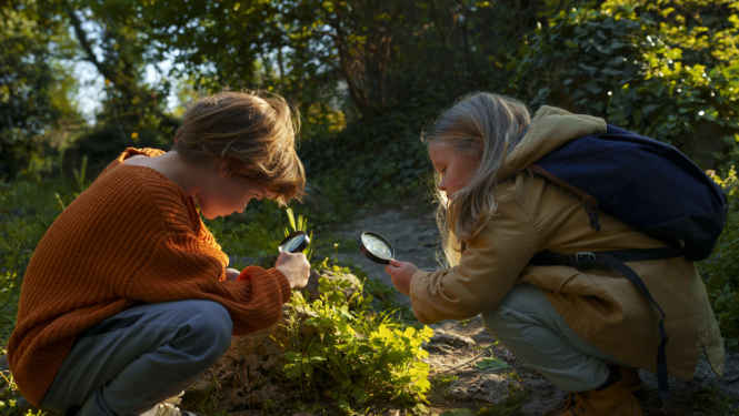 Bērni pēta augu ar lupu