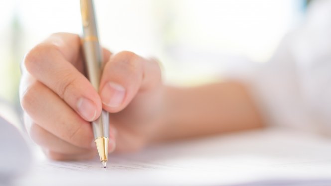 Cilvēka roka tur pildspalvu un raksta