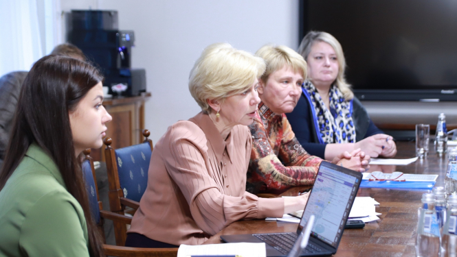 Ministre Anda Čakša sēž pie galda un sarunājas ar sporta skolotājiem