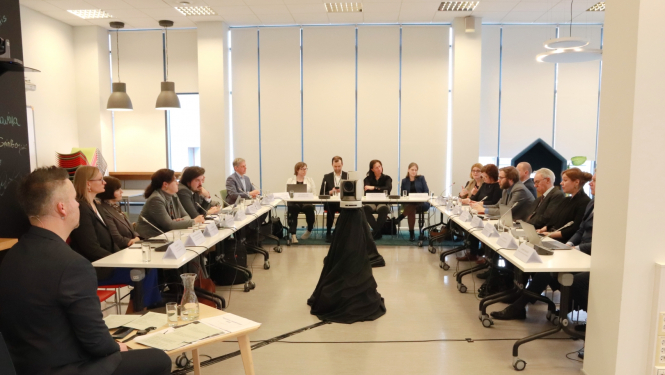 Akadēmiskās ētikas diskusijas dalībnieki sēž pie galdiem