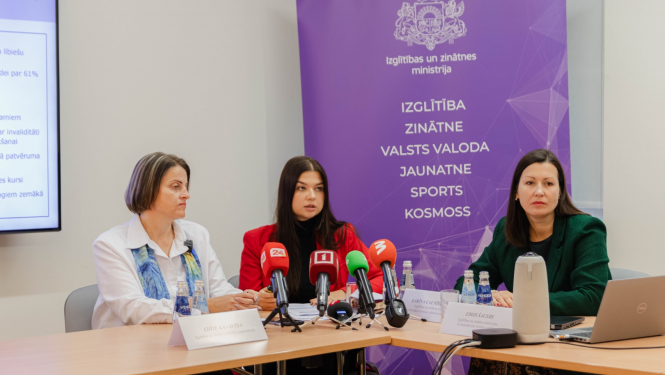 Pie galda sēž Edīte Kanaviņa, Silvija Amatniece un Karīna Caunīte-Orupe. Uz galda mediju mikrofoni, fonā uz violeta fona IZM logo un uzskaitītas zinātņu nozares: izglītība, zinātne, valsts valoda, jaunatne, sports, kosmoss