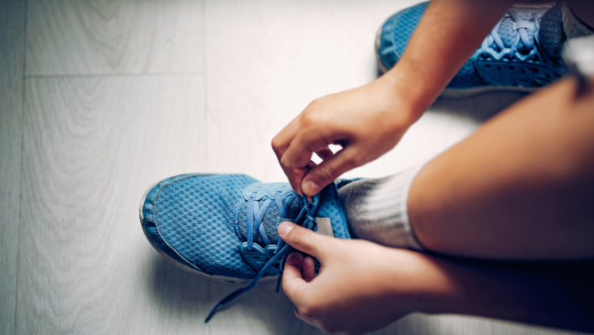 Cilvēka rokas sasien sporta apavu šņores