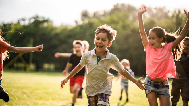 Priecīgi bērni skrien pa zālienu
