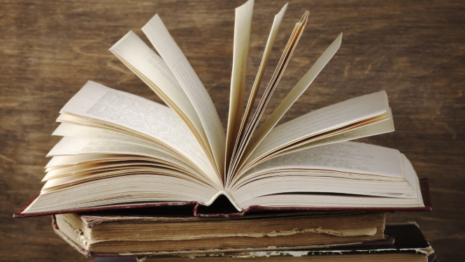 Vairākas vecas grāmatas, augšējā ir atvērta