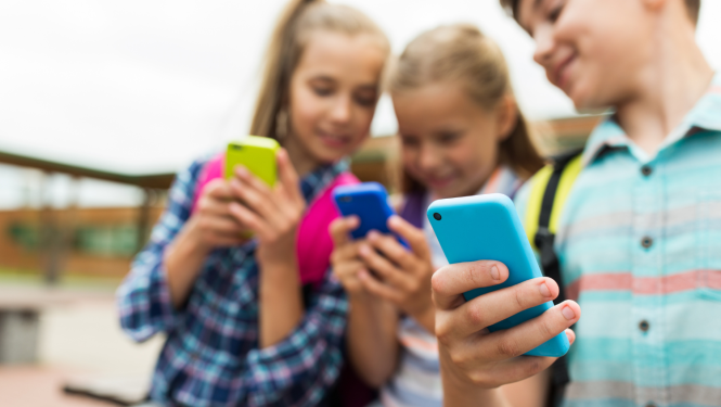 Trīs bērni ar mobilajiem telefoniem rokās