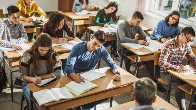 Jaunieši sēž klasē un mācās, priekšā sēž skolotājs