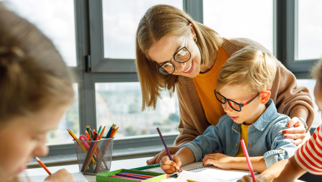 Skolotāja palīdz skolēnam pildīt mācību uzdevumu